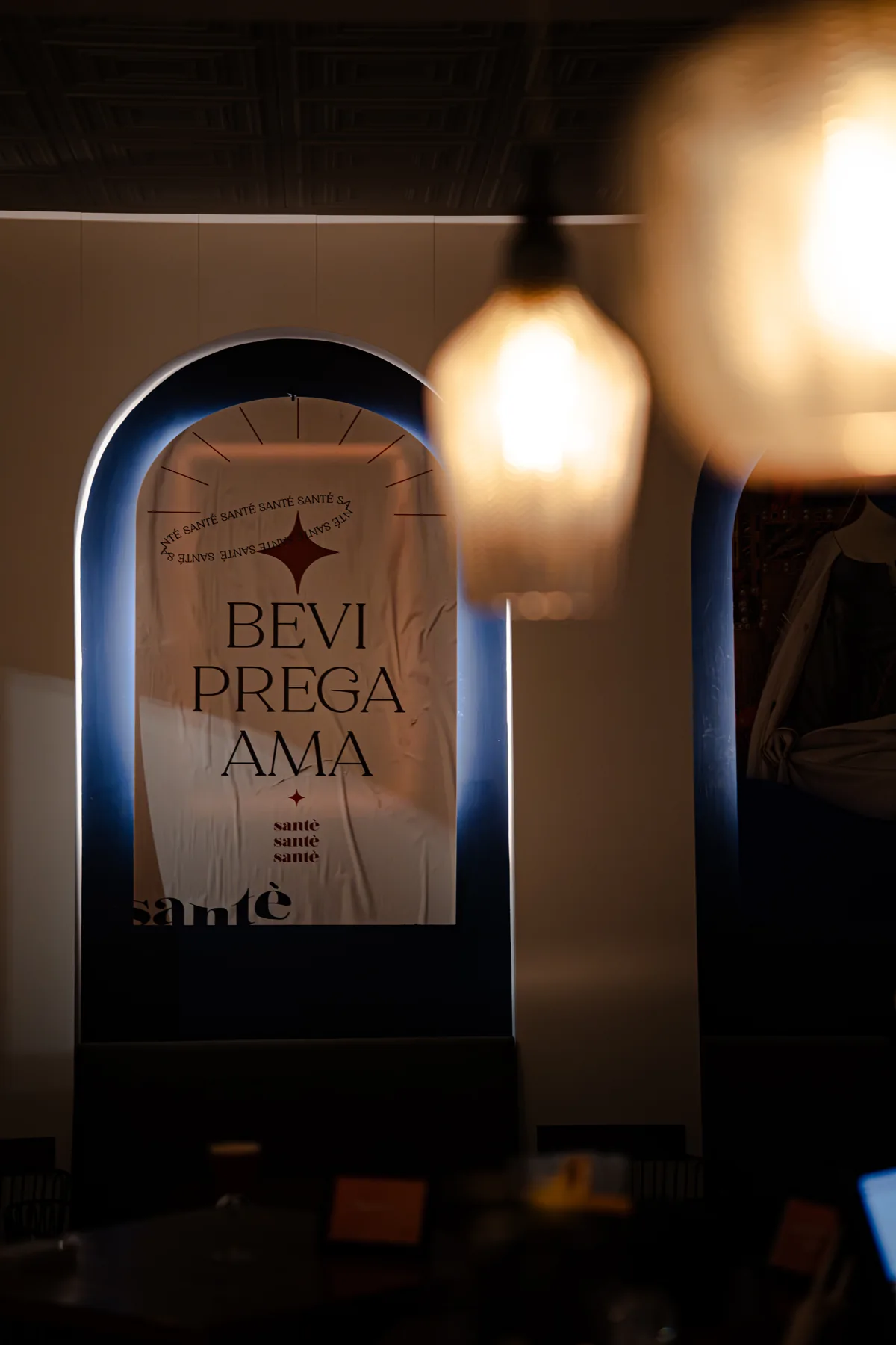 Le luci sospese e la scritta Bevi Prega Ama nella sala di Santé