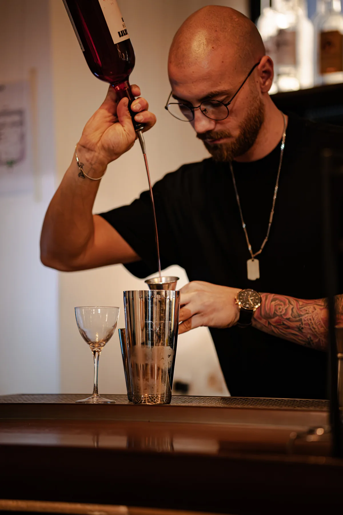 Il bartender di Santé versa dalla bottiglia nel misurino sopra lo shaker